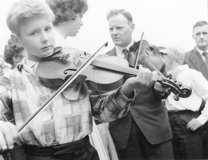 Young boy and man playing fiddle at the Fleadh Cheoil, Gorey, 1962 / Bord Fáilte